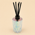 Iridescent Reed Diffuser with black reed sticks in a diamond-cut iridescent glass vessel
